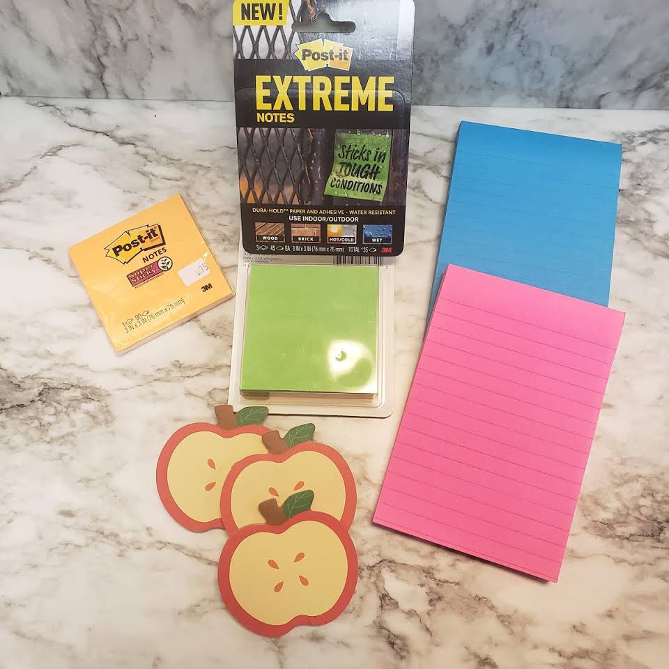 A marble counter top with sticky notes, sticky notes, and an apple stickers